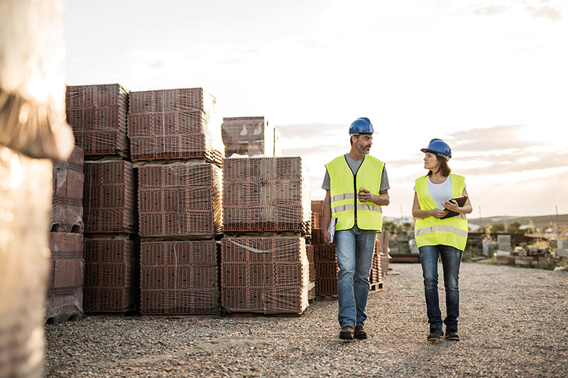 Man and woman, construction co-workers eat snack and chat amicably after exhausting day at sunset